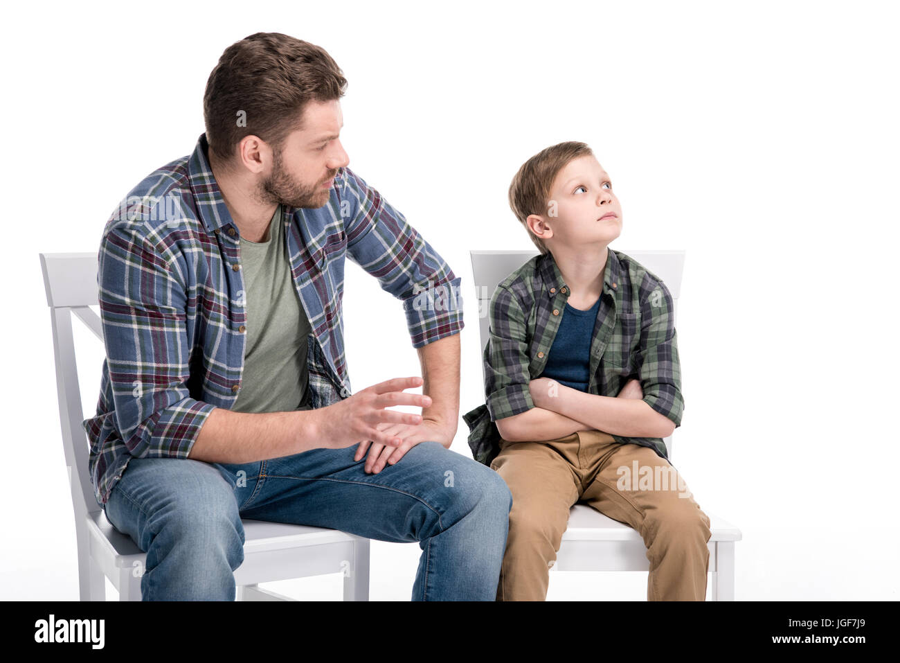 Father talking with little son sitting on chair with crossed arms and looking up, family problems concept Stock Photo