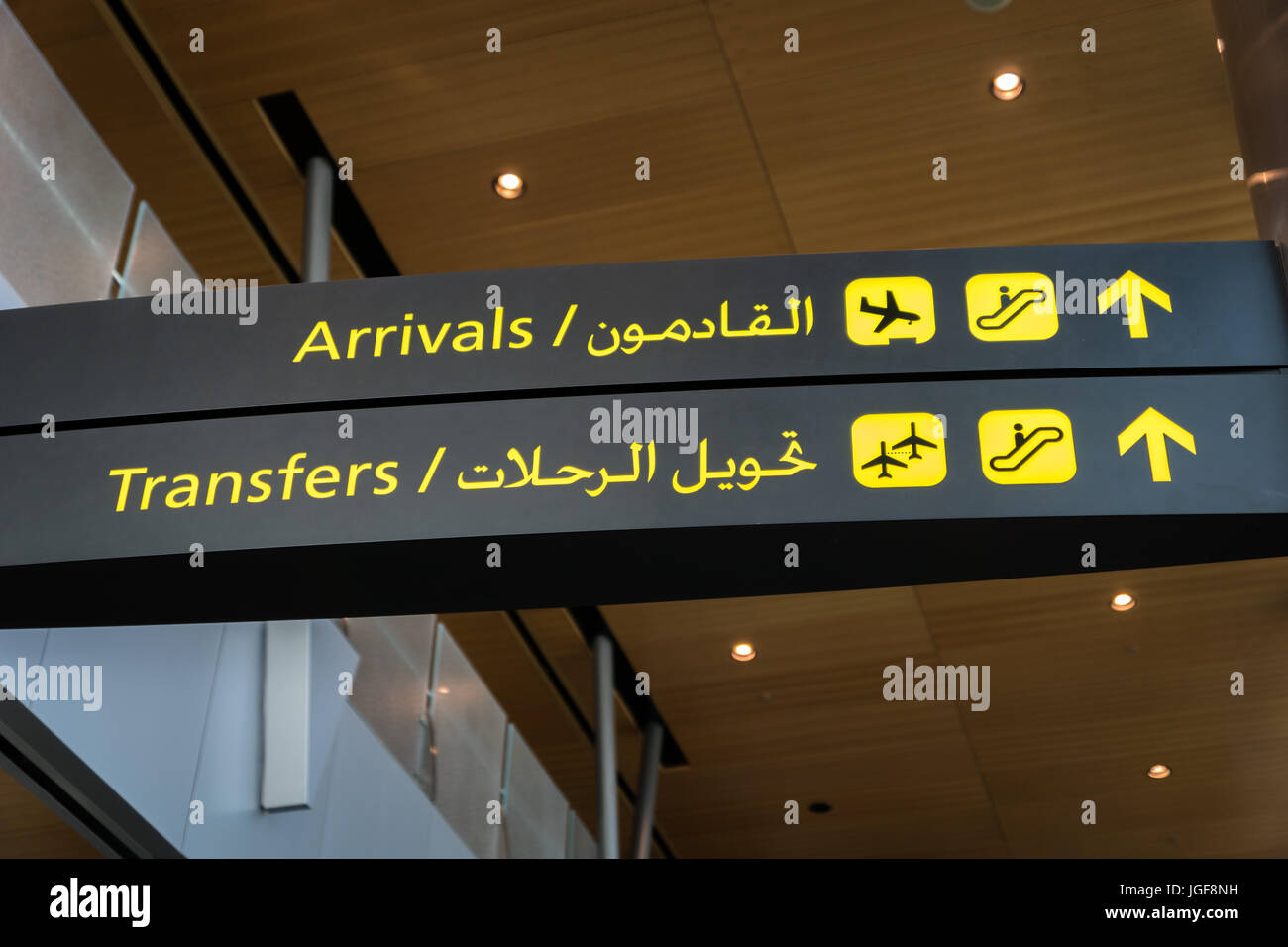 Airport arrival sign and transfer sign - flight arrival and transfer yellow sign at airport in English and Arabic Stock Photo