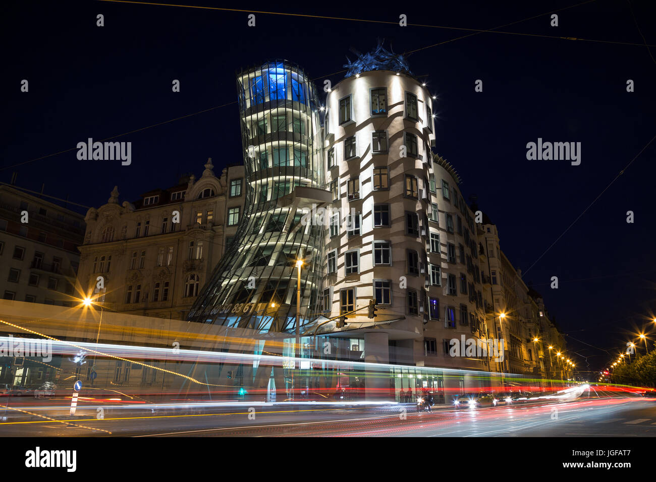 Light trails in front of the lit Dancing House building in Prague at night. The building was designed by the Croatian-Czech architect Vlado Milunic. Stock Photo