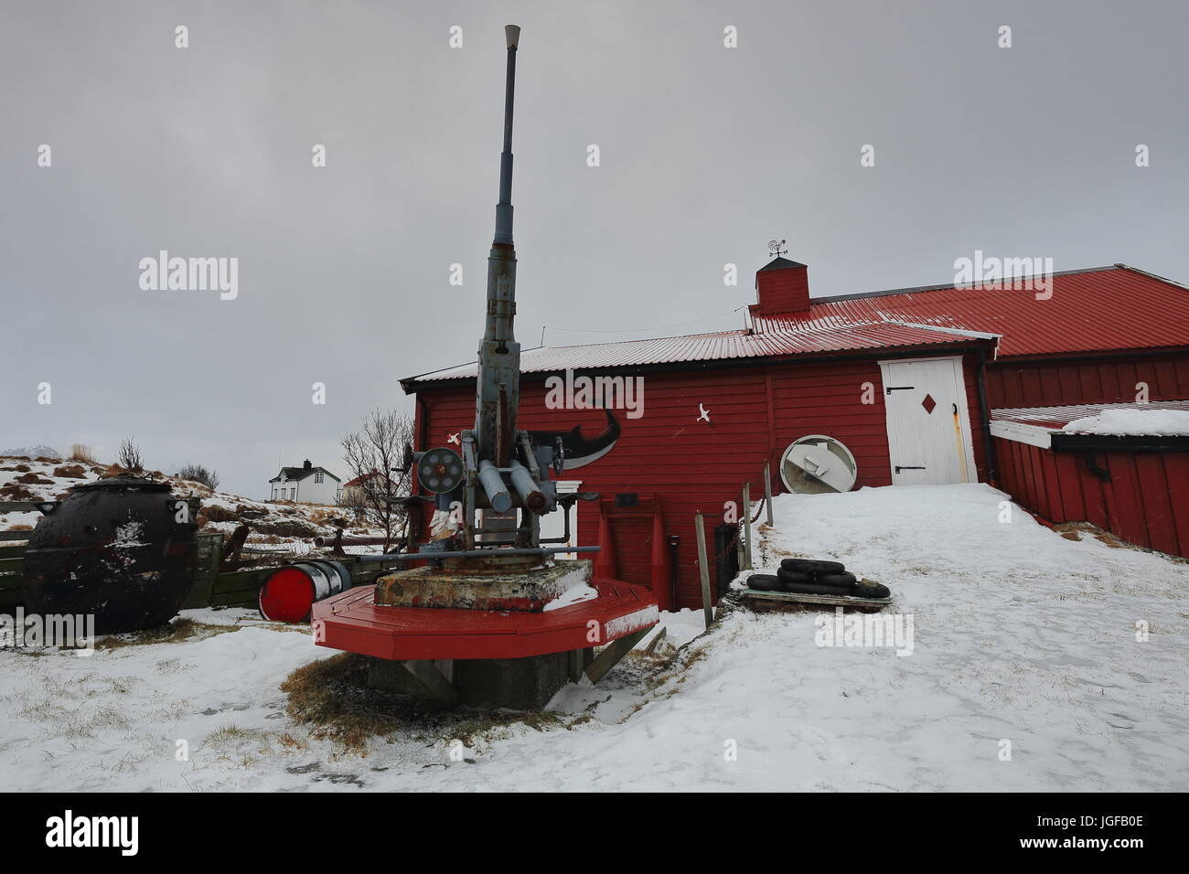 Anti-aircraft machine gun placed along with other weapons in the garden of an eccentrically decorated red-white townhouse in Nordmela-Andoya island-Lo Stock Photo