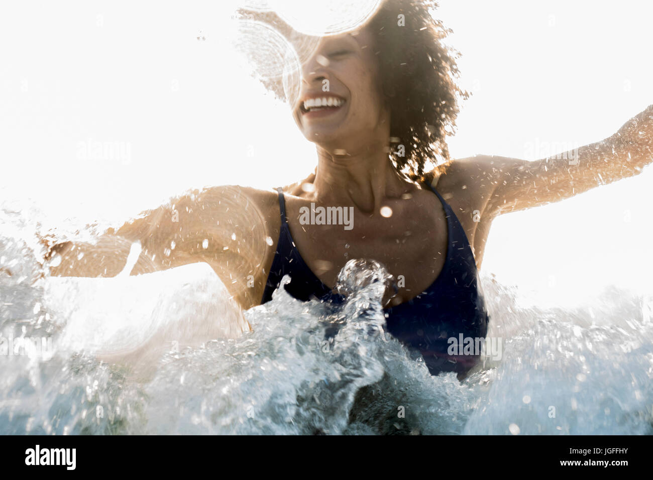 Ocean waves splashing on Mixed Race woman Stock Photo