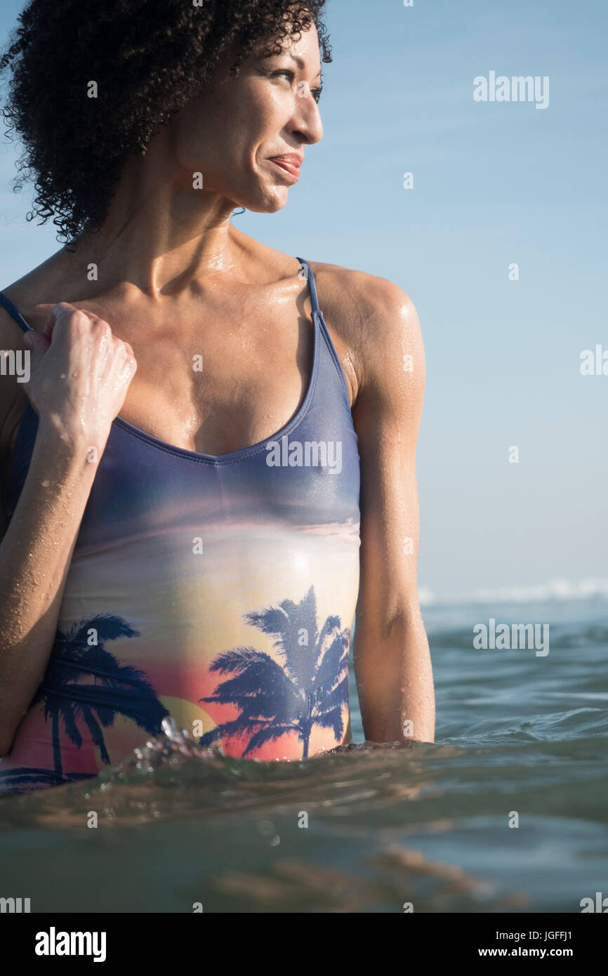 Mixed Race woman wading in ocean Stock Photo