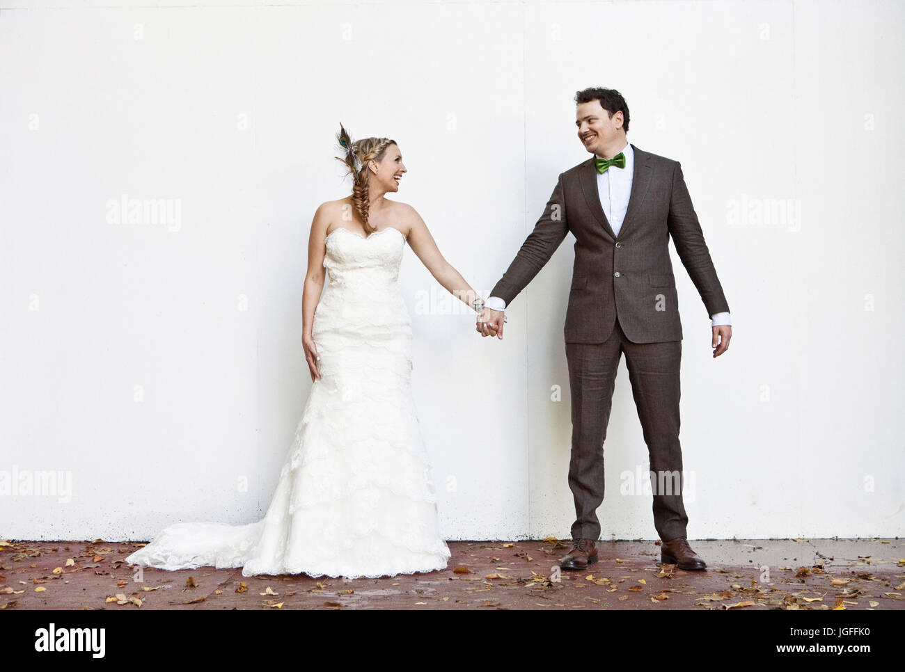 Smiling Caucasian bride and groom holding hands Stock Photo