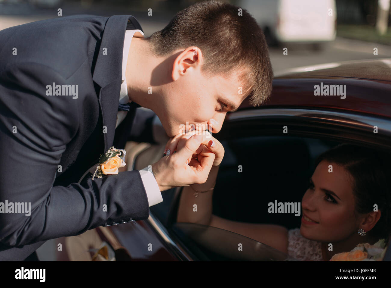 The groom is kissing the hand of the sitting in the car bride Stock ...