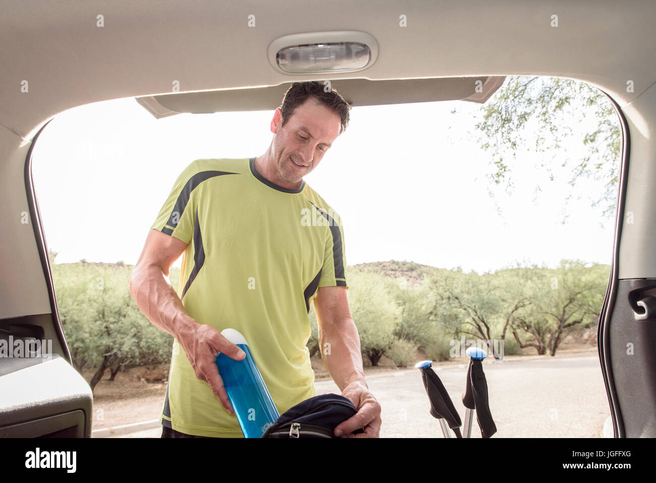 Hispanic man pulling water bottle from backpack in car Stock Photo