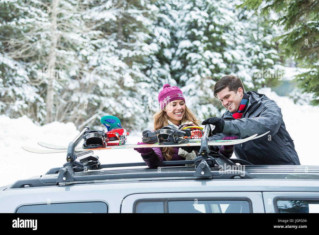Caucasian couple checking snowboards in car roof rack Stock Photo Alamy