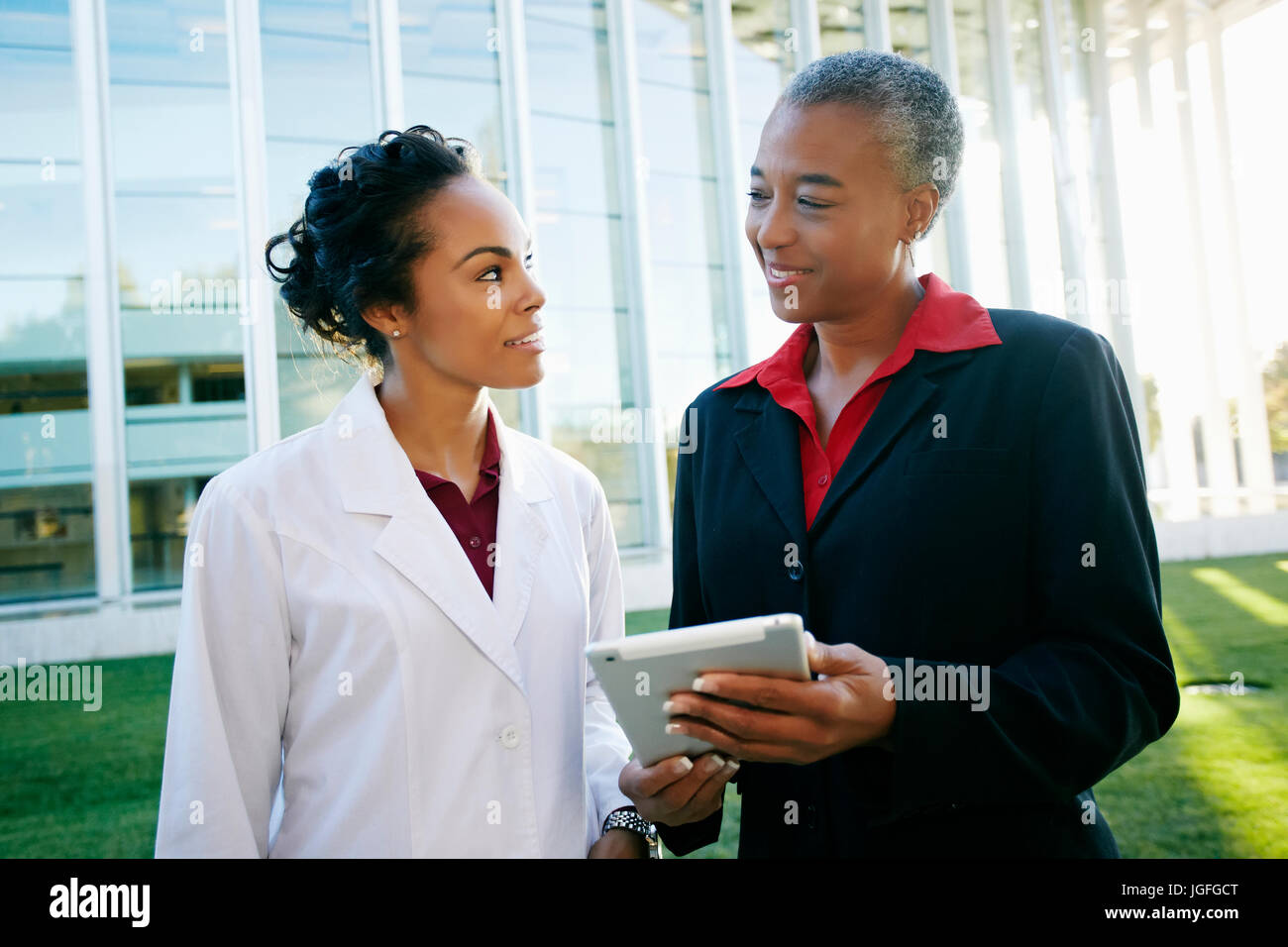 Doctor and administrator outdoors at hospital using digital tablet Stock Photo