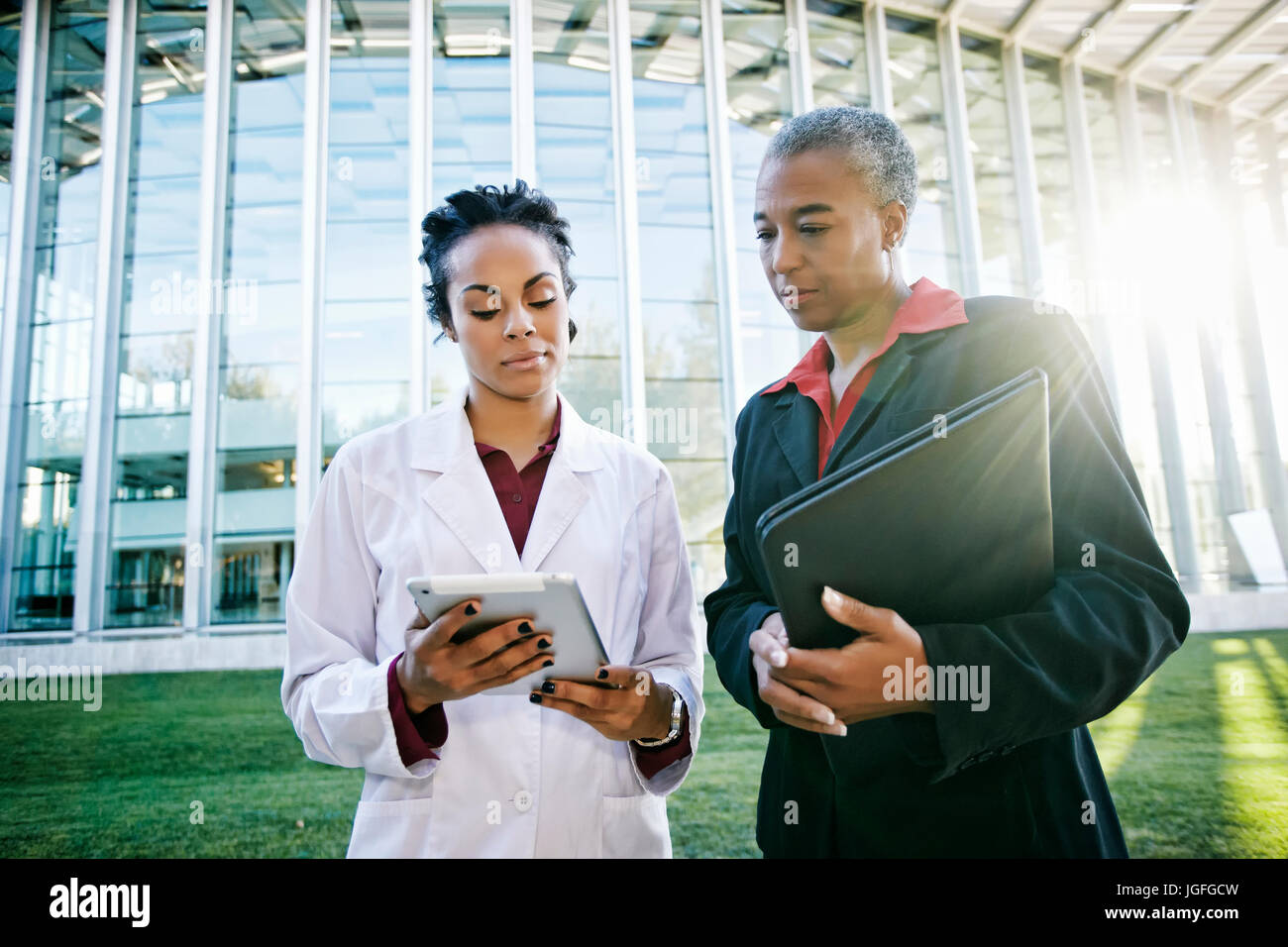 Doctor and administrator outdoors at hospital using digital tablet Stock Photo
