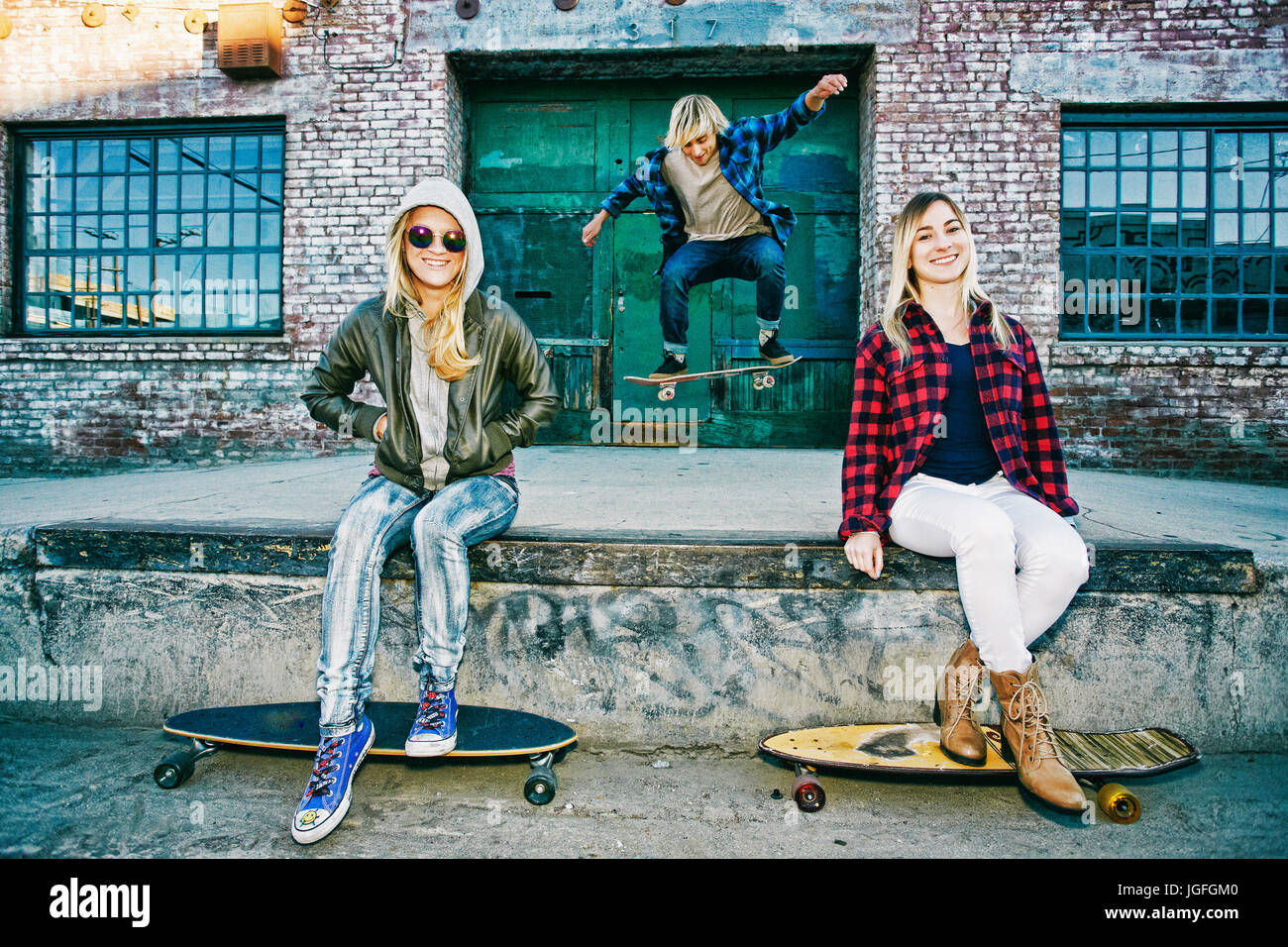 Friends with skateboards smiling on loading dock Stock Photo