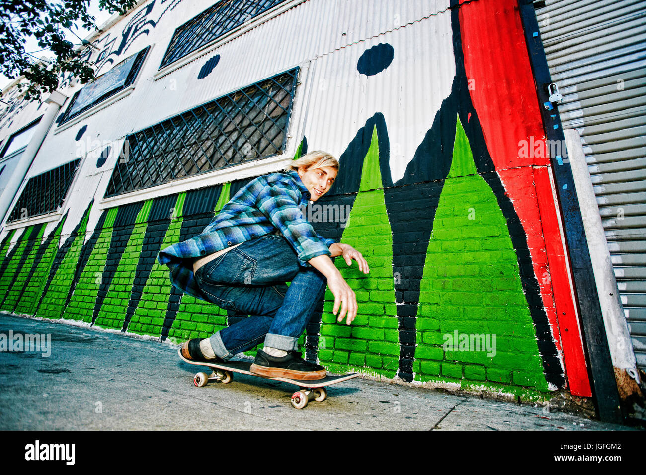Caucasian man skateboarding on urban sidewalk Stock Photo