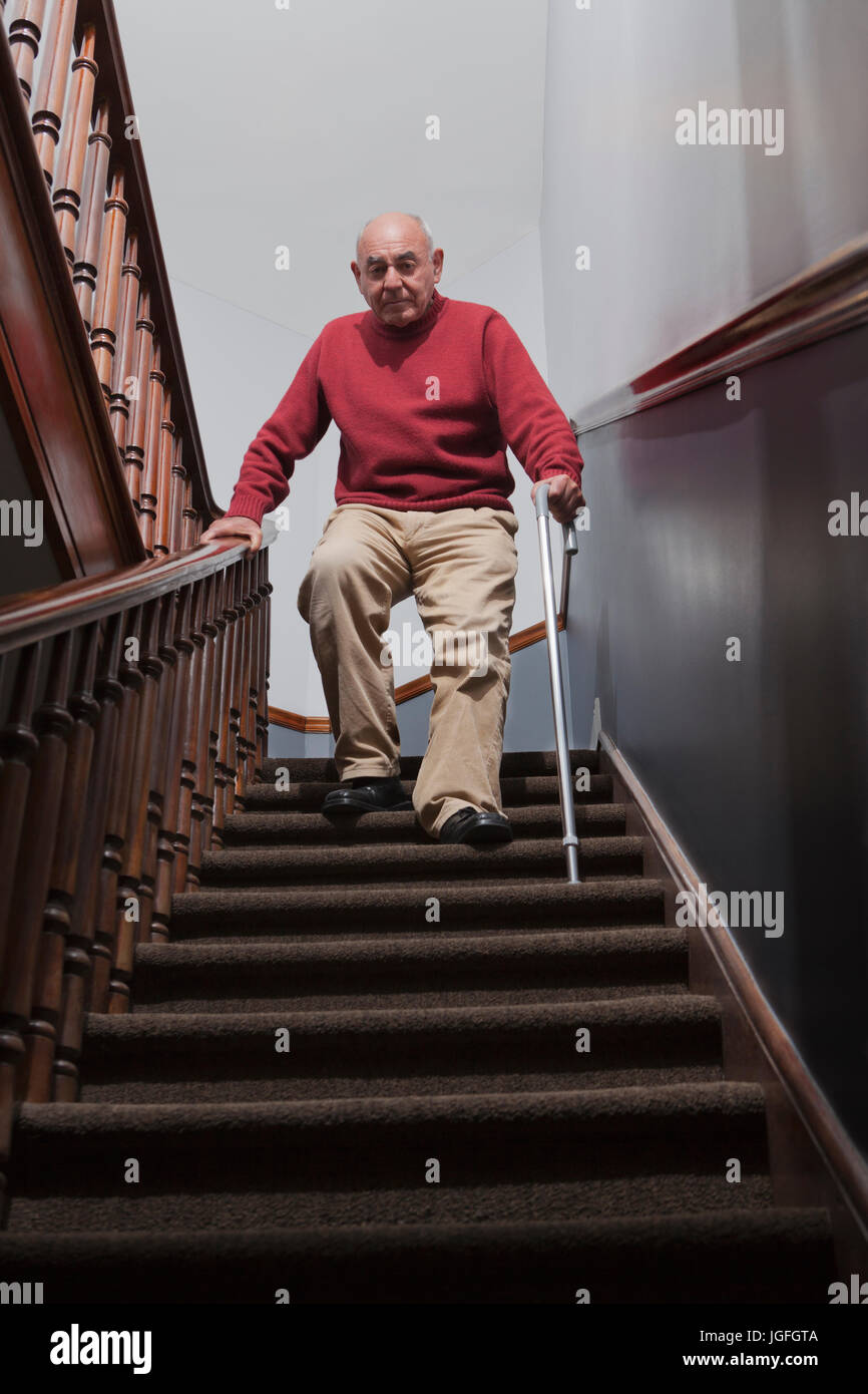 Hispanic man with cane descending staircase Stock Photo