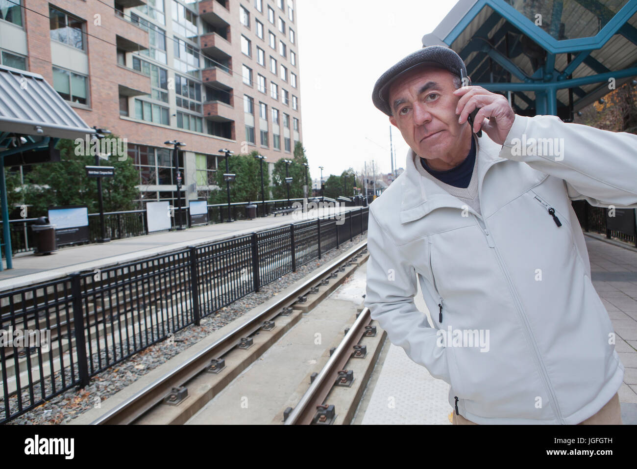 Hispanic man waiting at train station talking on cell phone Stock Photo