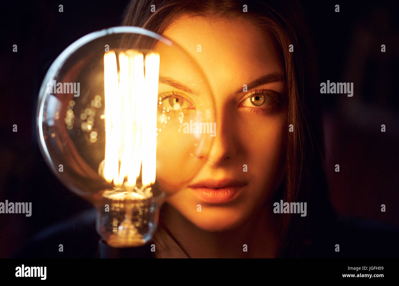 Face of Caucasian woman illuminated by energy efficient light bulb Stock Photo