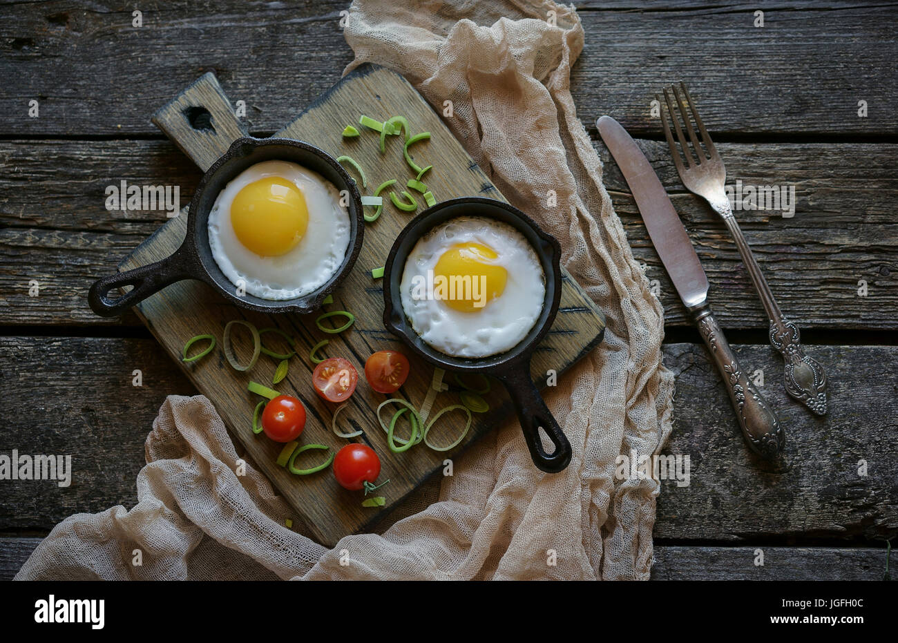 Fried eggs in cast iron pans on cutting board Stock Photo