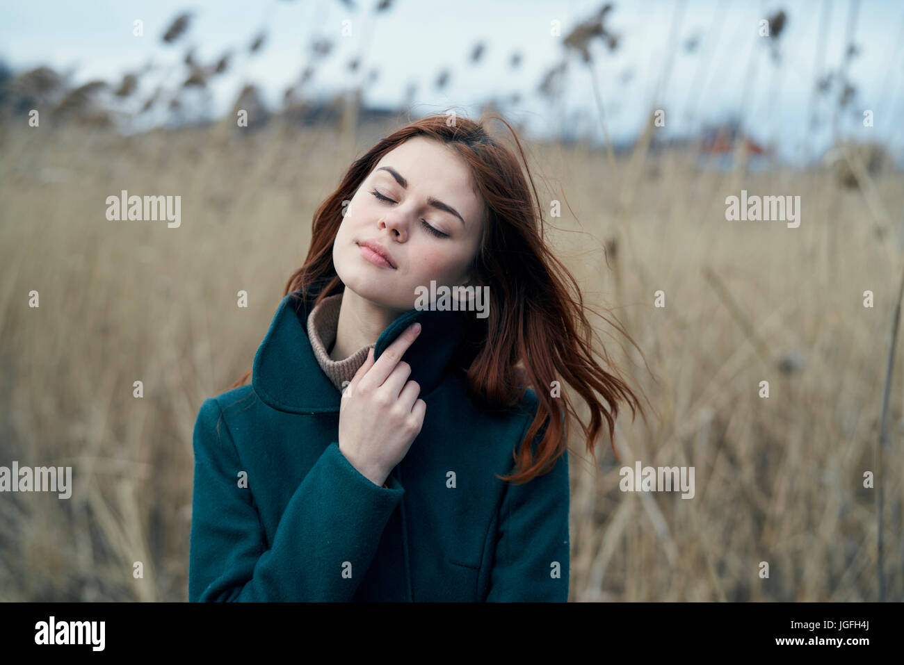 Pensive Caucasian woman standing in field holding collar Stock Photo