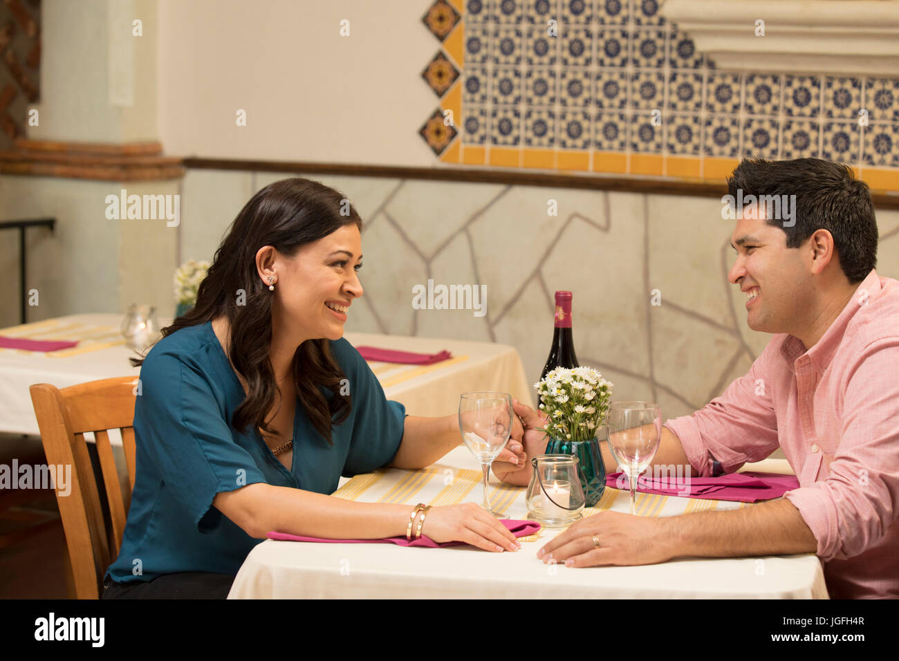 Hispanic couple holding hands at table in restaurant Stock Photo
