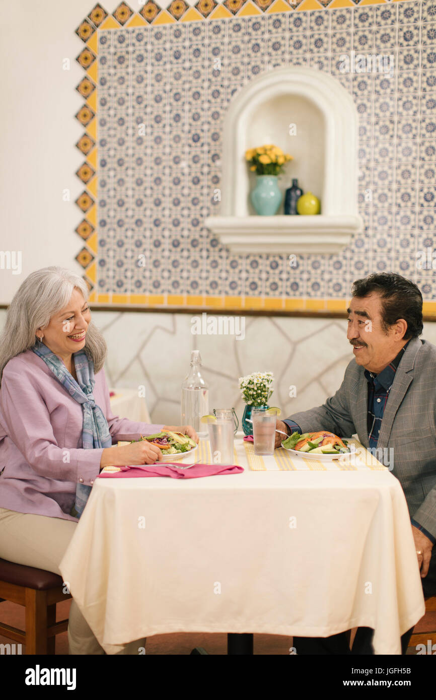 Smiling older couple eating salad and laughing in restaurant Stock Photo