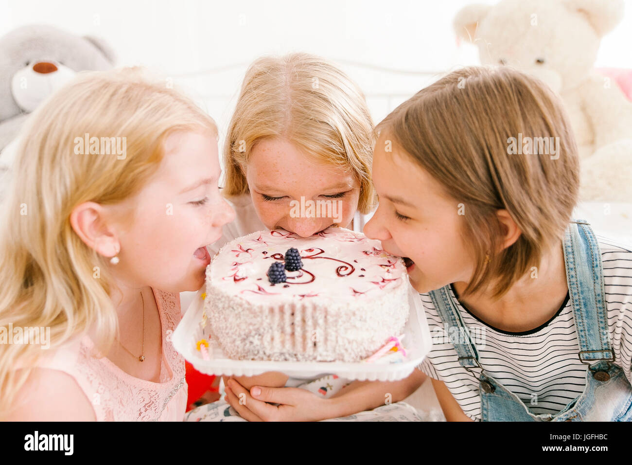 Middle Eastern sisters biting birthday cake Stock Photo - Alamy