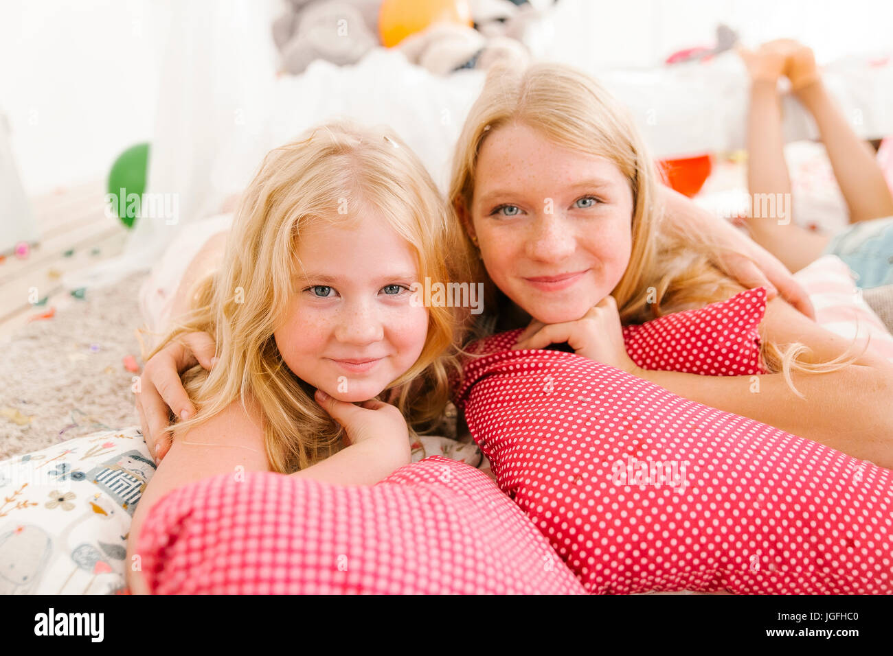 Portrait of smiling Middle Eastern sisters laying on floor Stock Photo
