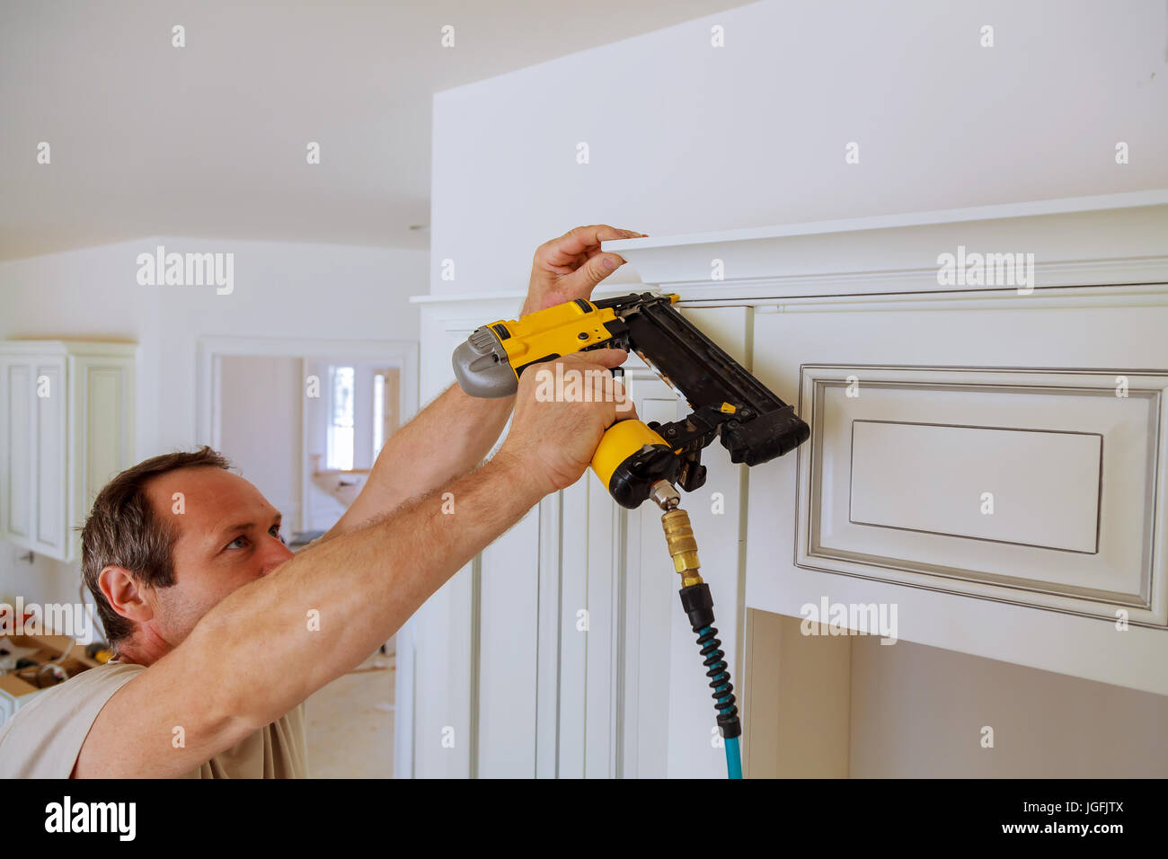 Carpenter brad using nail gun to Crown Moulding on kitchen