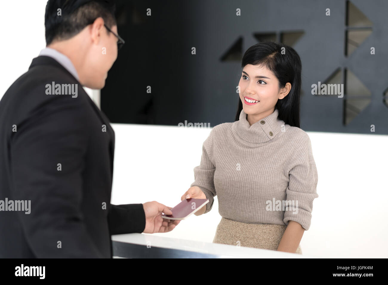 Asian Beautiful girl at the reception of a hotel checking in with businessman. Stock Photo