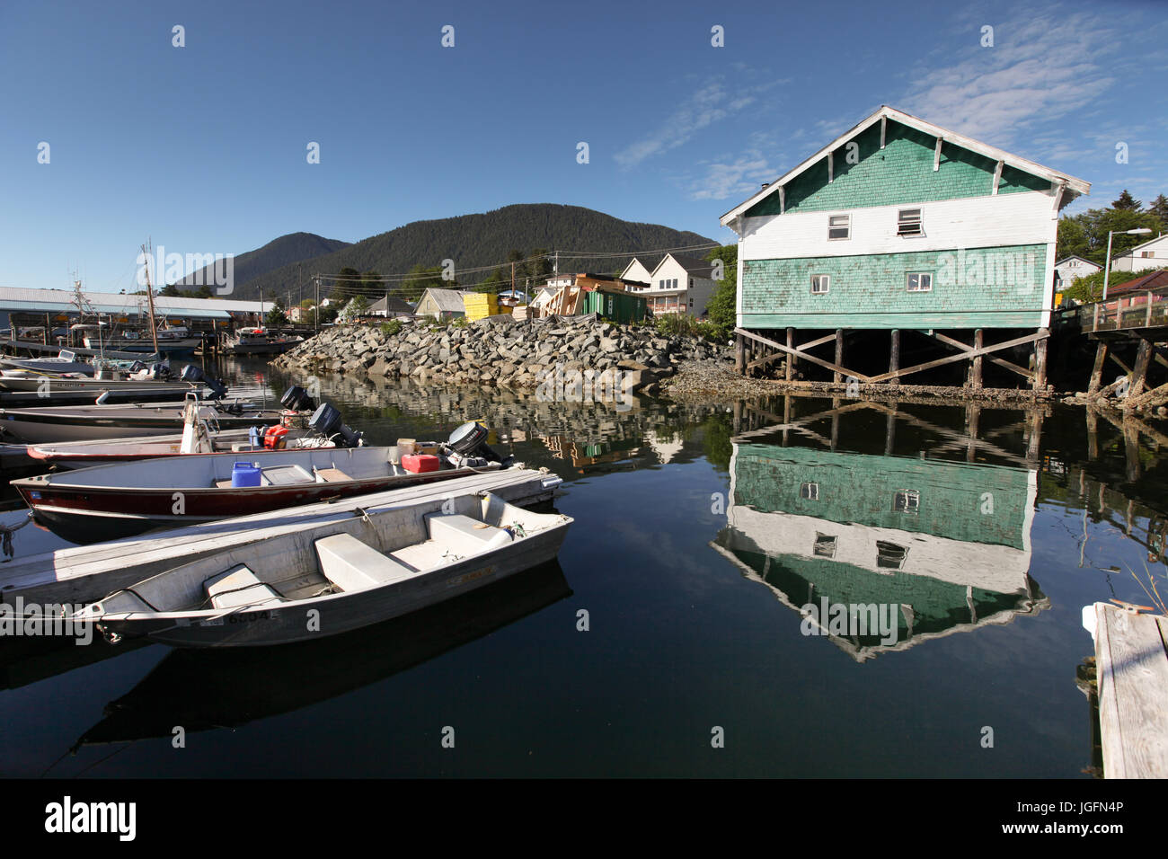 A waterfront home on stilts is reflected in the water filled with nearby fishing boats. Stock Photo