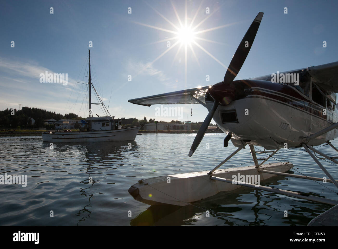 Under bright sun, a seaplane sits in the water near a passenger boat. Stock Photo