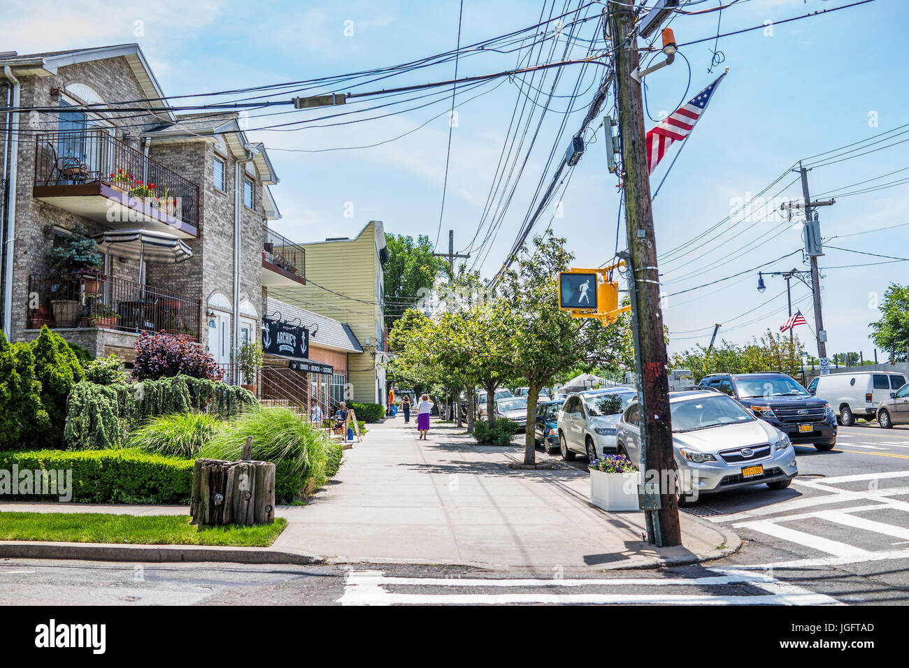 Bronx, USA - June 11, 2017: City Island road with sidewalk and restaurants with American flags Stock Photo