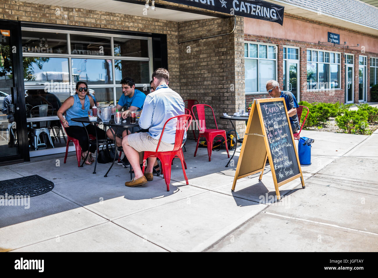 Bronx, USA - June 11, 2017: People eating brunch outside at outdoor seating area with tables in City Island at Archie's restaurant with sidewalk Stock Photo