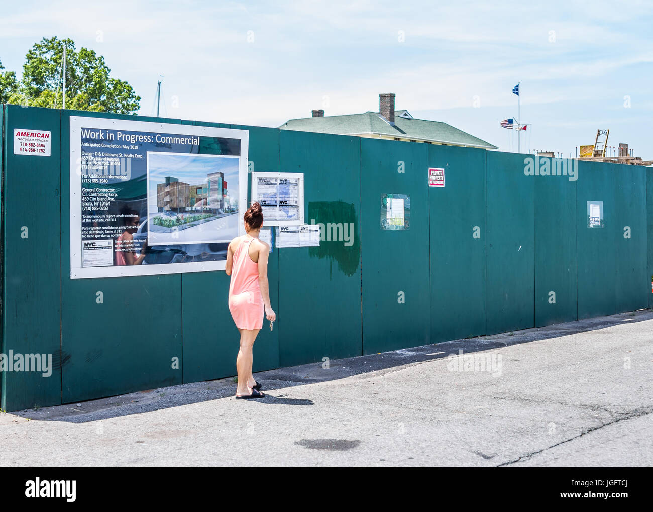 Bronx, USA - June 11, 2017: City Island road with signs of new construction and young woman reading Stock Photo