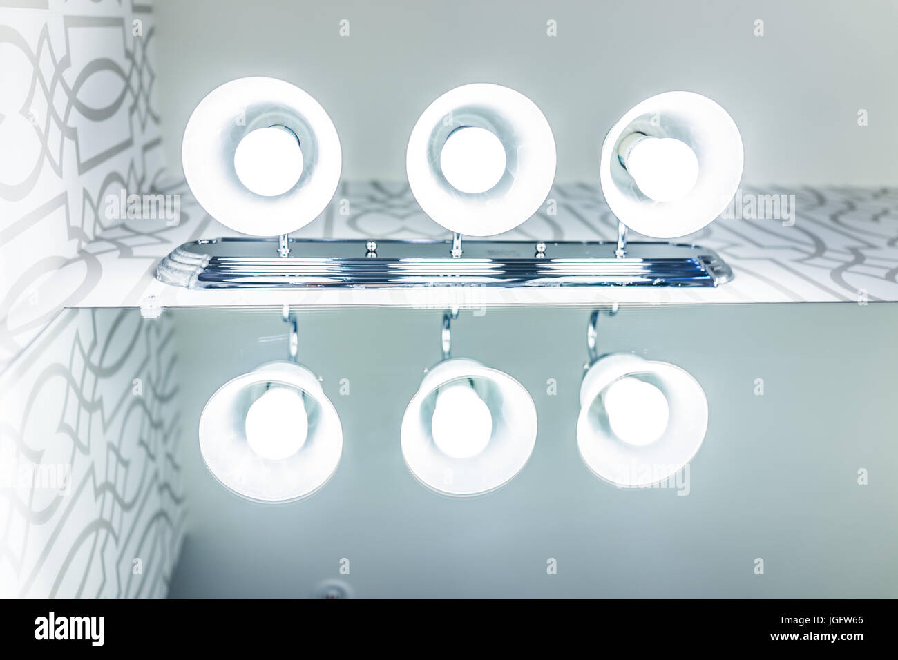 Closeup of three bathroom light fixtures with reflection on mirror Stock Photo