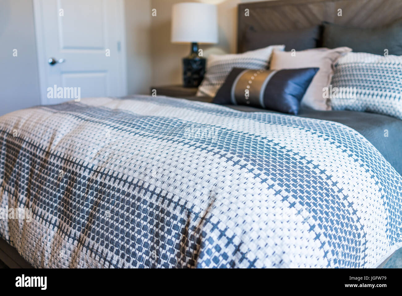 Closeup of new bed comforter with decorative pillows in bedroom Stock Photo