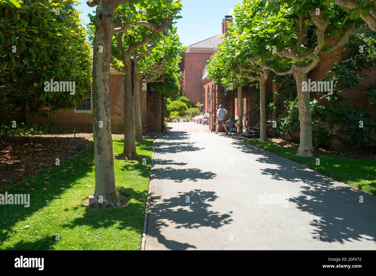 Approach to the main house, with a gardener performing maintenance tasks, at Filoli, a preserved country house, formal garden and estate operated by the National Trust for Historic Preservation in Woodside, California, June 23, 2017. Stock Photo