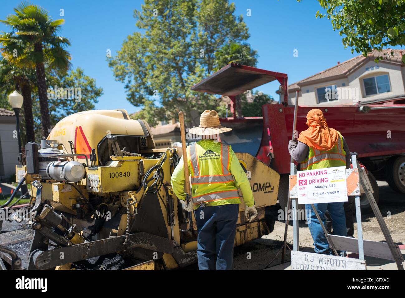 Construction workers for American Asphalt work to lay a new road surface, wearing wide brimmed hats and turbans to protect themselves from the bright sun, during a road construction and resurfacing project in the San Francisco Bay Area suburb of San Ramon, California, June 26, 2017. Stock Photo