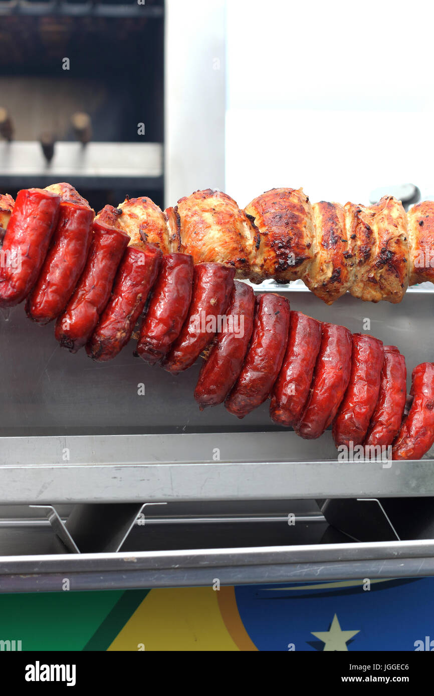 Chorizo sausages and roast chickens on Charcoal Spit Roaster BBQs Stock Photo