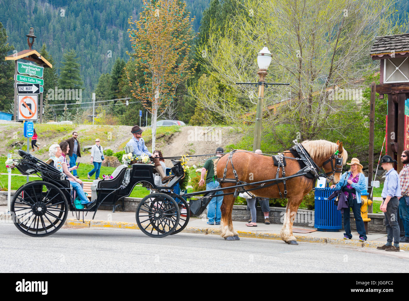 Carriage and horse with tourists and men in lederhosen in Bavarian Village of Leavenworth, Washington Stock Photo