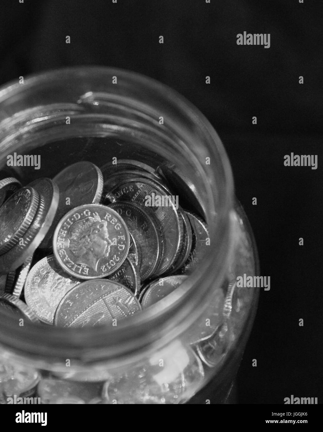 Collection of coins in a glass jar Stock Photo