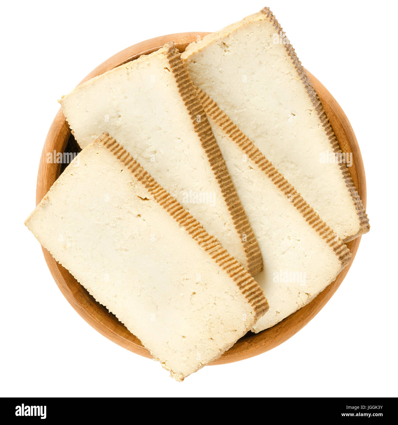 Smoked tofu slices in wooden bowl. Bean curd. Coagulated soy milk, pressed into firm white blocks. Component of Asian cuisine. Meat substitute. Stock Photo