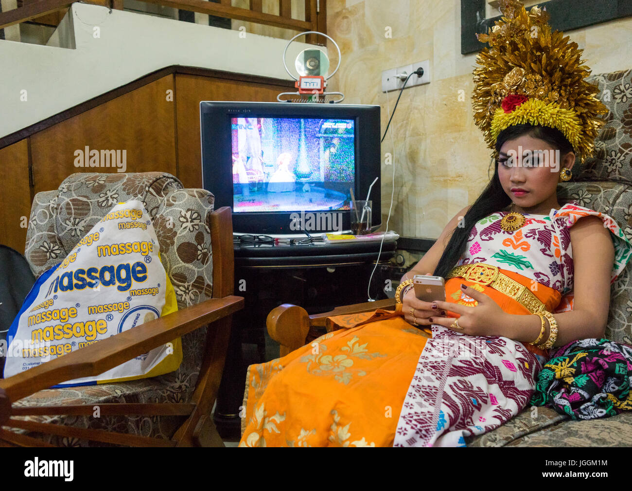 A teenage girl in traditional costume using her mobile phone as a mirror before a tooth filing ceremony, Bali island, Canggu, Indonesia Stock Photo