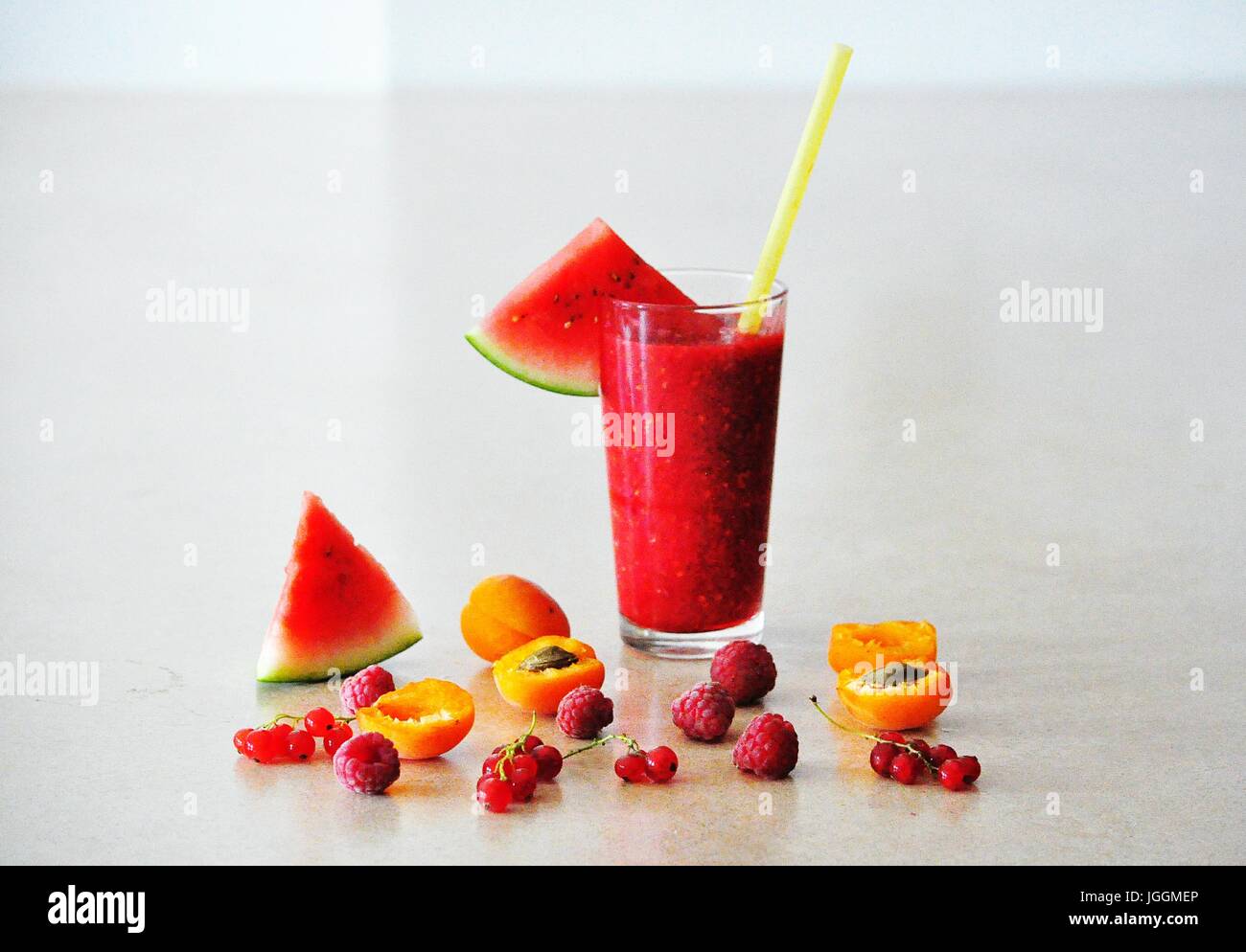 Still life with summer smoothie drinks in glasses on the table decorated with fruits and berries - watermelon, apricot, raspberry, red currant Stock Photo