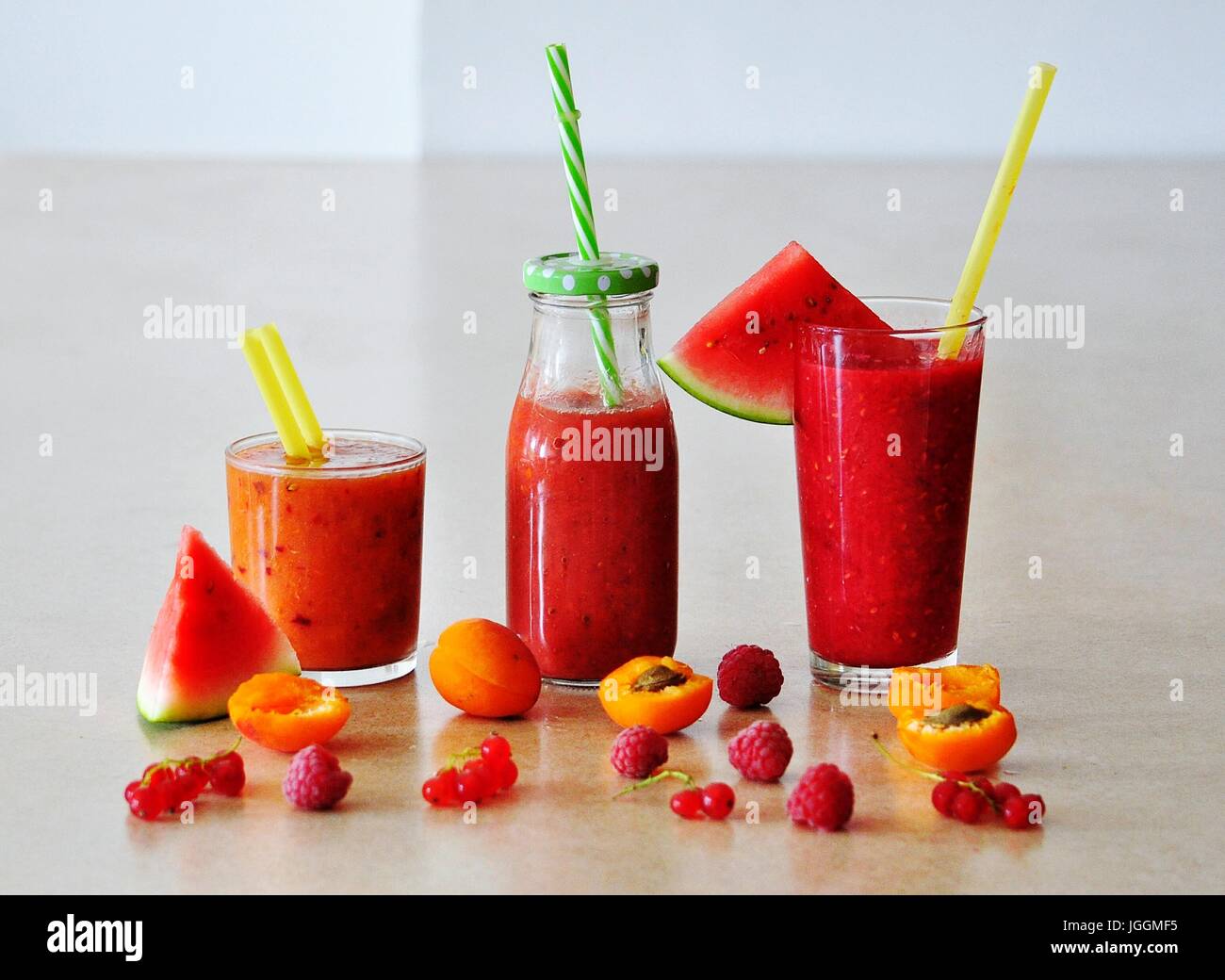 Still life with summer smoothie drinks in glasses on the table decorated with fruits and berries - watermelon, apricot, raspberry, red currant Stock Photo