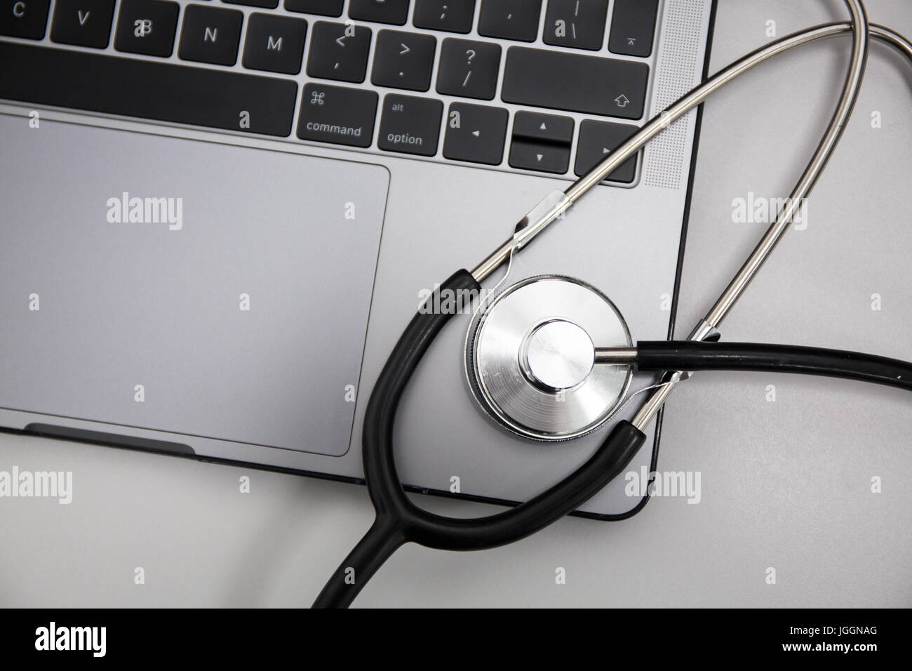 Laptop and stethoscope on flat grey background, Horizontal. Stock Photo
