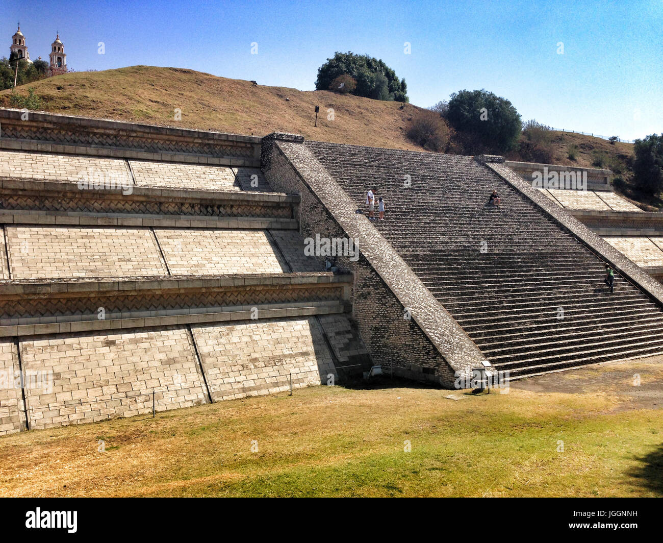 View of the Great Pyramid of Cholula, Tlachihualtepetl, one of the largest prehispanic structures in the world with people climbing the steps to the c Stock Photo