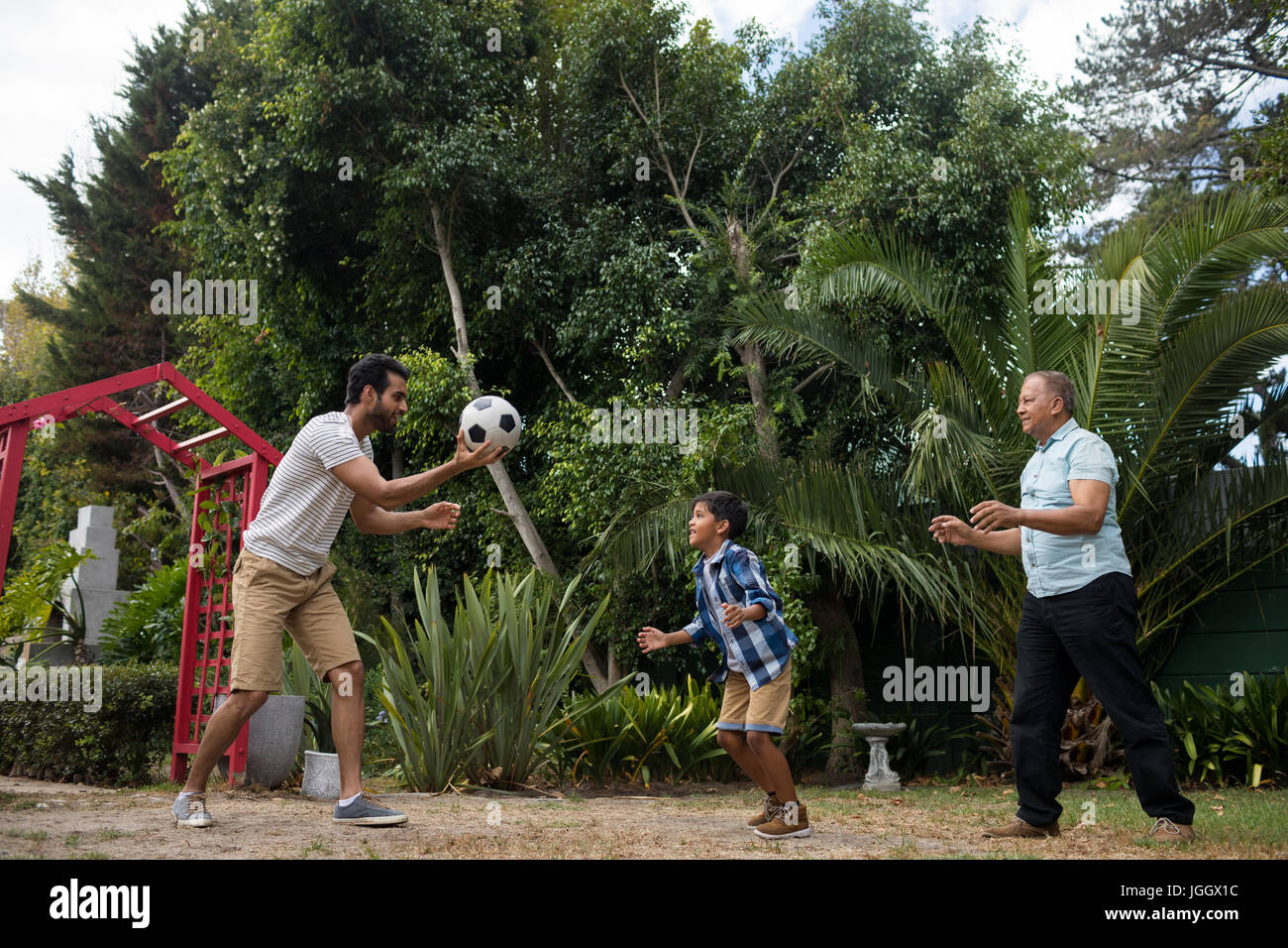 Happy family playing soccer against plant at park Stock Photo - Alamy