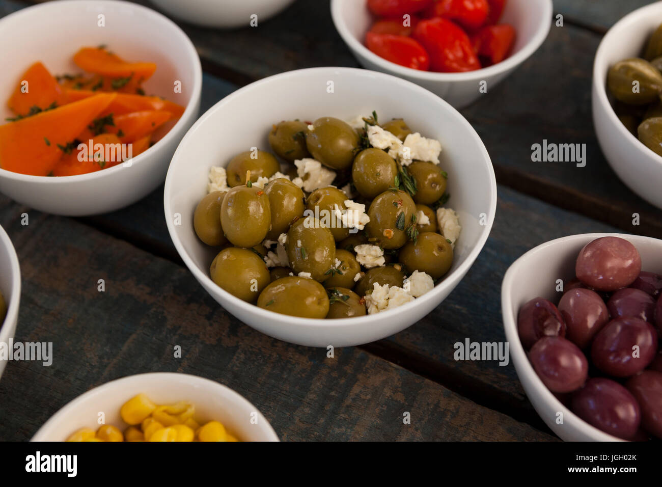 Close up of green olives with cheese by various food in bowls on table Stock Photo