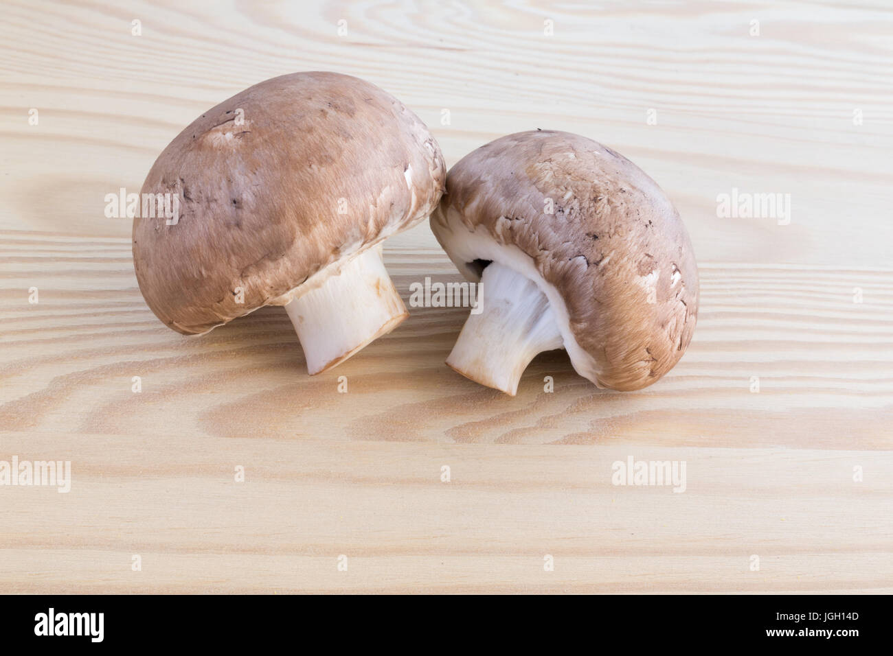 Two chestnut mushrooms on a wooden cutting board Stock Photo