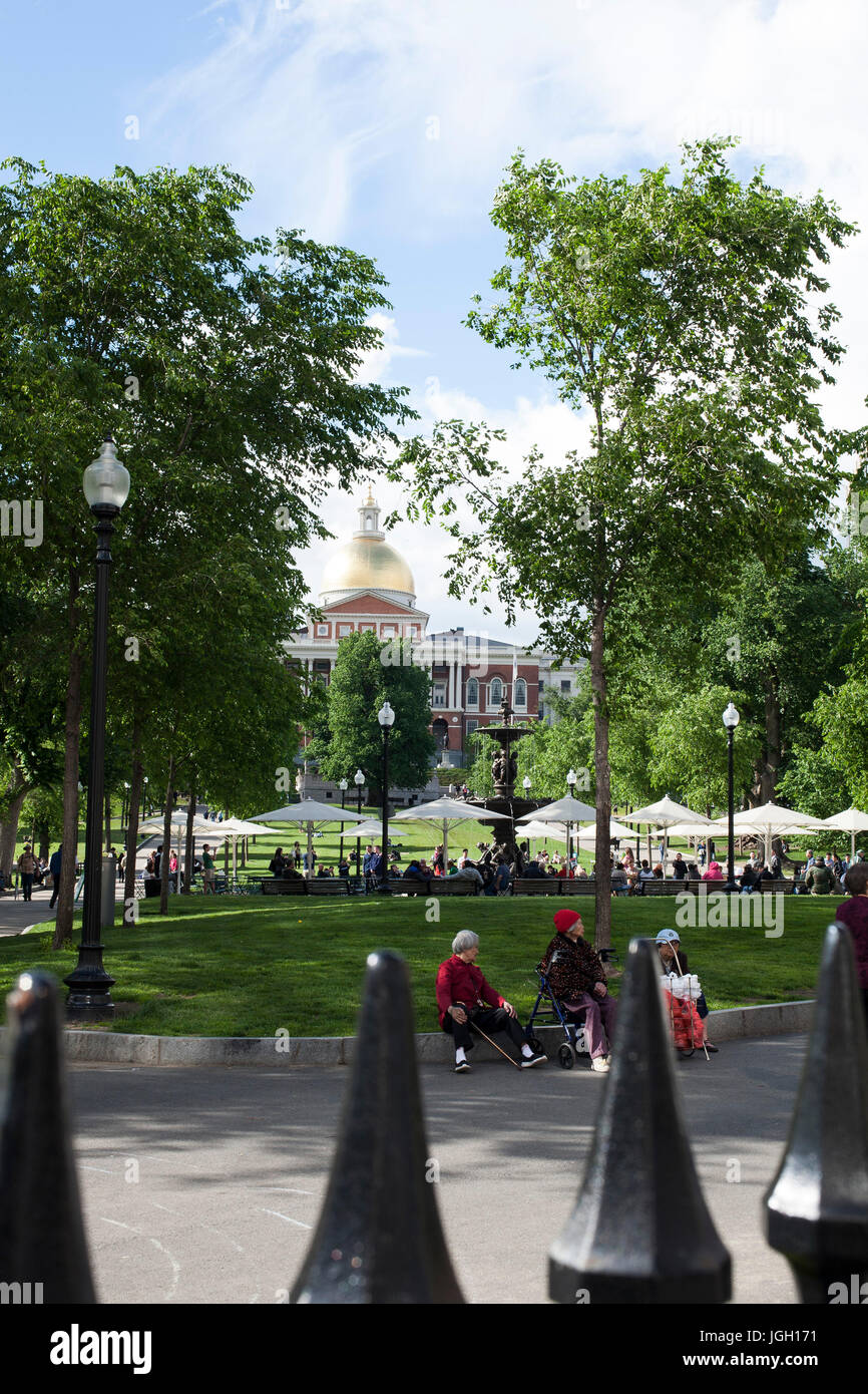 Spiked wrought iron fence is in the foreground of a view of the Boston Common and State House. Stock Photo