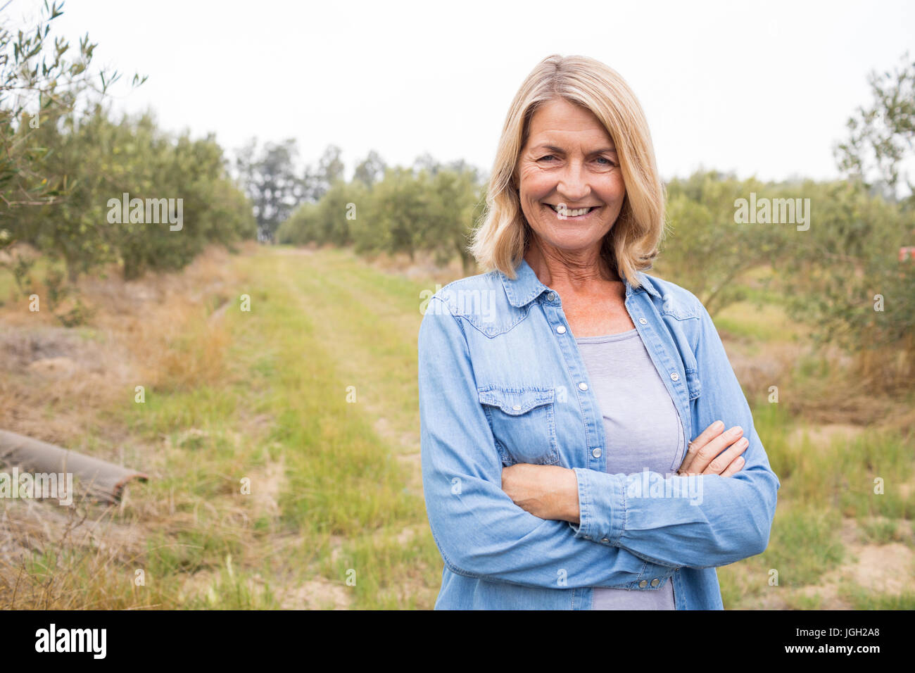 Portrait of happy woman standing with arms crossed in olive farm Stock ...