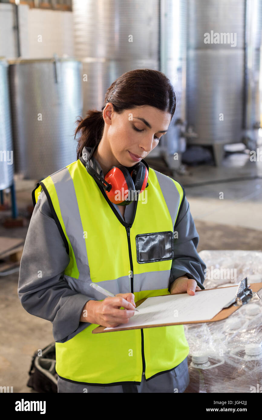 Female technician writing in clipboard at oil factory Stock Photo - Alamy