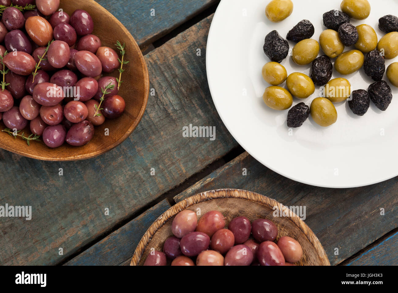 Overhead view of olives in bowls and plate on wooden table Stock Photo